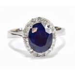 A white metal diamond and sapphire cluster ring, the modified brilliant cut sapphire weighing approx