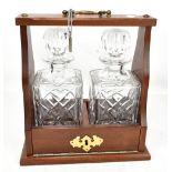 A modern tantalus housing two clear glass decanters, height including swing handle 29cm, with key.