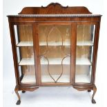 An early 20th century mahogany display cabinet with carved gallery above astragal glazed central