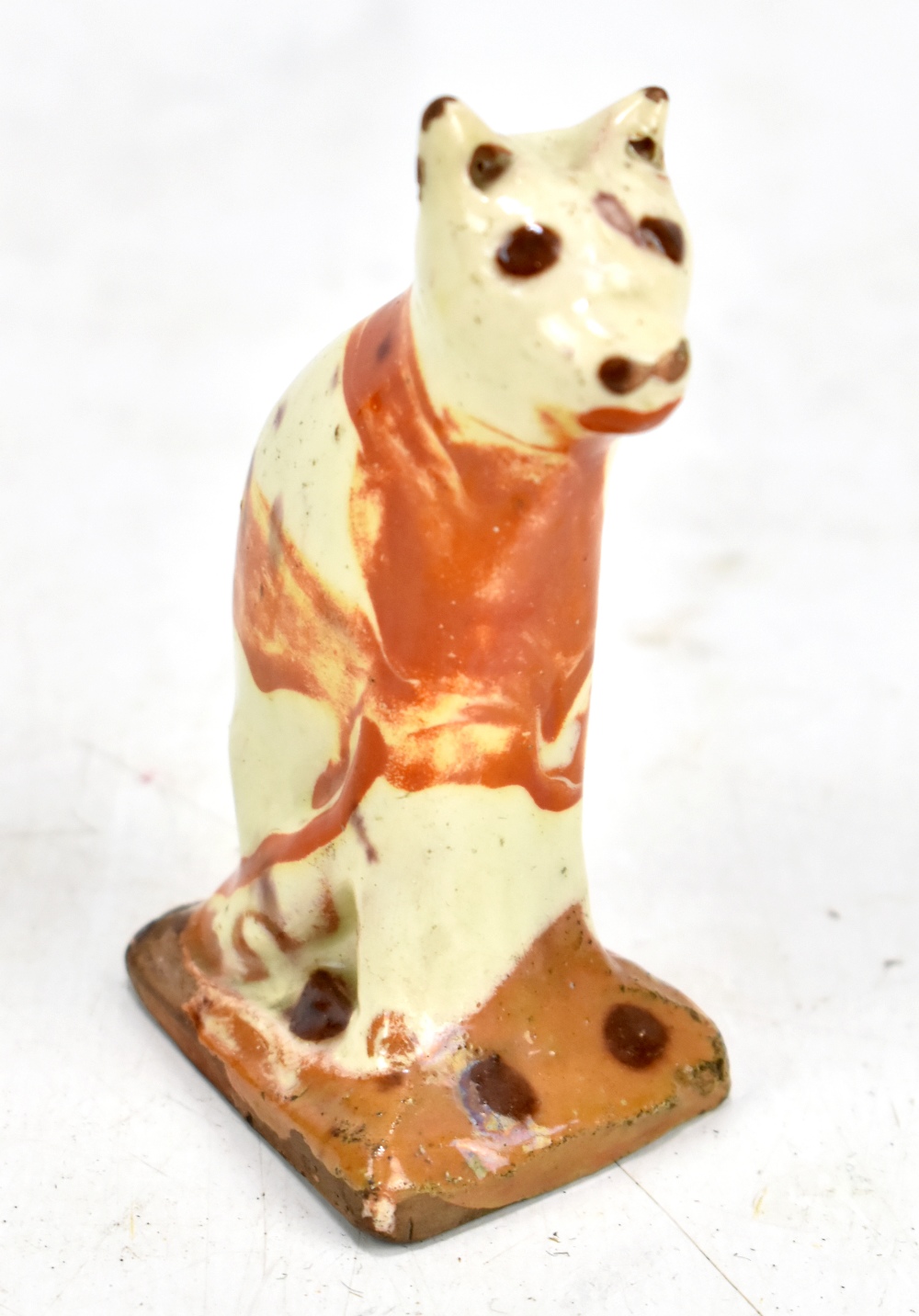 An early 19th century Bovey Tracey cream glazed model of a seated cat, height 8.7cm.Additional