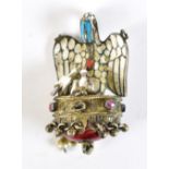 A circa 1850 German gilt metal and enamelled religious pendant depicting a pelican pecking its own