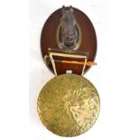 An equestrian themed wall mounted brass gong suspended from a patinated horse's head.