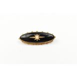 A late Victorian/Edwardian yellow metal mourning brooch or oval form, with central cut pearl and