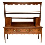 An 18th century oak dresser with plate rack back, the back with two thick shelves and two panelled