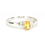 An 18ct white gold yellow sapphire and diamond ring of Art Deco design, the oval sapphire weighing
