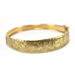 A 9ct yellow gold hinged snap bangle with floral engraved detail, approx 9.5g, internal width approx