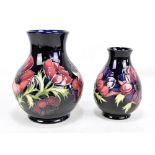 MOORCROFT; two tubeline decorated 'Anemone' pattern baluster vases on navy grounds, marked to