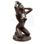 A contemporary bronzed metal water feature modelled as a kneeling nude lady on naturalistically