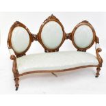 A Victorian triple back settee, the three oval back panels with carved detail, raised on tapering