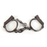 A pair of 19th century wrought iron handcuffs numbered 159 and stamped 'Warranted Wrought', with