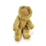 A miniature blonde plush teddy bear with glass eyes and jointed limbs, length approx 9.5cm.