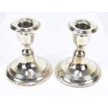 WILLIAM AITKEN; a pair of George V hallmarked silver squat form candlesticks, each with linear