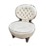 An ebonised button back upholstered nursing chair raised on turned front legs.