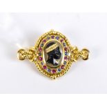 An unusual yellow metal Blackamore brooch, with central carved profile bust within a border of