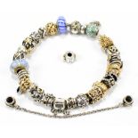 PANDORA; a hallmarked silver charm bracelet featuring seven yellow metal charms all stamped 585