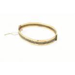 A 9ct yellow gold hinged snap bangle, with safety chain, approx 17.4g.