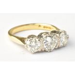 An 18ct yellow gold and diamond three stone ring, the central round brilliant cut stone weighing