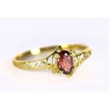 A yellow metal dress ring set with red coloured oval cut stone and white stone chips, stamped 375 to