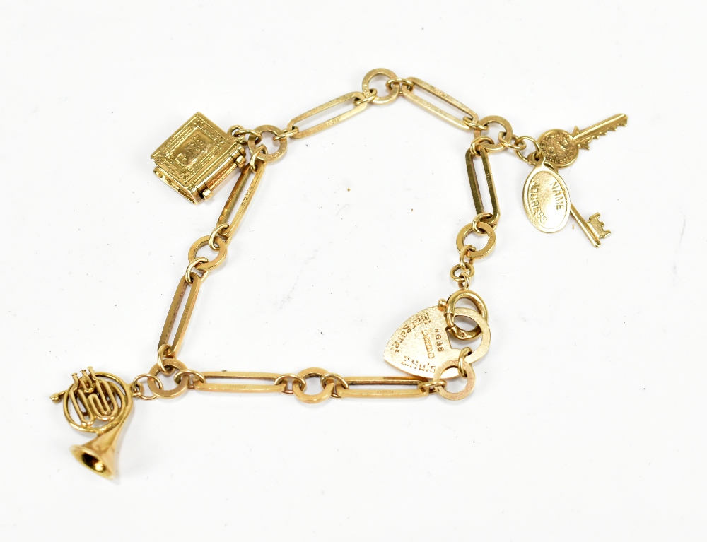 A 9ct yellow gold charm bracelet set with a French horn, book, pair of keys and with padlock