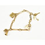 A 9ct yellow gold charm bracelet set with a French horn, book, pair of keys and with padlock