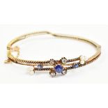 A late Victorian/Edwardian yellow metal diamond seed pearl and sapphire hinged snap bangle, unmarked