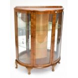 An early 20th century Art Deco burr walnut veneered display cabinet of shaped outline with twin