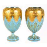 A pair of late 19th century pale blue opaque glass vases, with enamel decoration and gilded overlay,