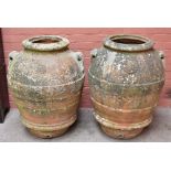 A near pair of 19th century twin handled terracotta olive jars, each with circular roundels, one