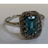 An Art Deco white metal diamond set cocktail ring with central emerald cut stone within a border