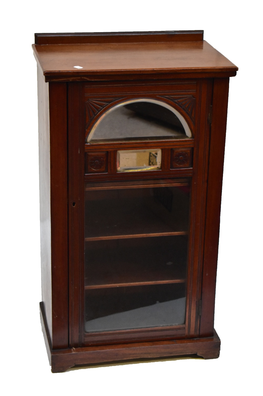 A Victorian walnut music cabinet with carved detail and glazed door enclosing three shelves.