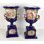 A large pair of Vienna porcelain transfer decorated urns with gilt heightening and raised on socle