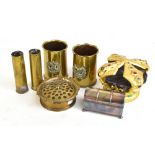 A small group of metal ware including trench art vases with applied cap badges and ash tray, a