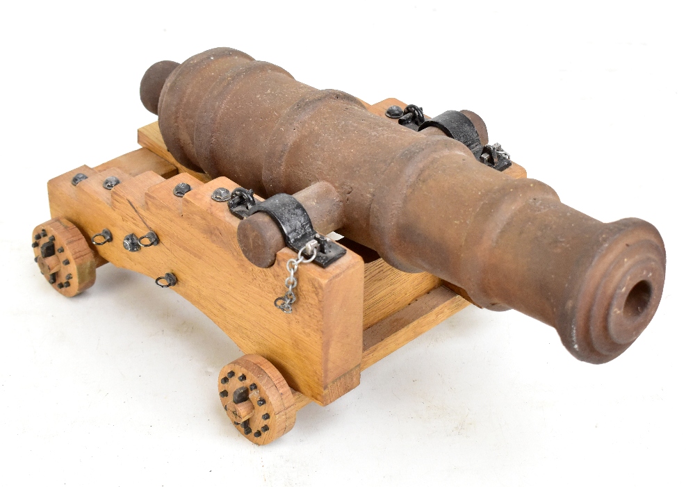 A cast iron tabletop model cannon, length 36cm, on wooden base with four wheels.Additional