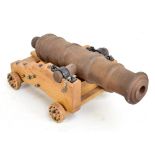 A cast iron tabletop model cannon, length 36cm, on wooden base with four wheels.Additional