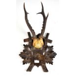 An early 20th century Black Forest carved stained beech wall plaque set with a pair of three point