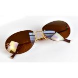 CHANEL; a pair of rimless tinted sunglasses with gold-tone nose and bars with Chanel logo to lenses,