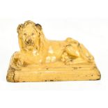 An early 19th century cream glazed pottery model of a recumbent lion with paws crossed, unmarked,