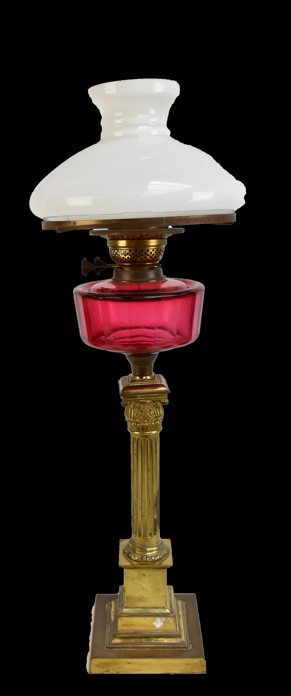 A Victorian brass oil lamp with faceted cranberry glass reservoir and milk glass shade, height 72cm.