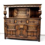 A reproduction oak court cupboard with heavily carved decoration of fern, floral and foliate motifs,