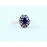 An 18ct gold cluster ring set with oval sapphire in a surround of twelve diamonds in a claw setting