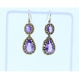 A pair of yellow metal drop earring set with amethyst in beaded surround.