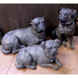 Three terracotta models of pug dogs, one in a recumbent pose,