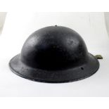 A WWII steel helmet painted black with original insert and webbing chin strap, stamped 1941.