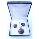 A white metal pendant set with rubies and a pair of matching earrings (2).