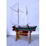 A large scratch-built wooden model of a sailboat, two mast sail, some remote control mechanism,