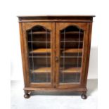 An early 20th century oak two-door display cabinet raised on squat bun feet, width 96cm,
