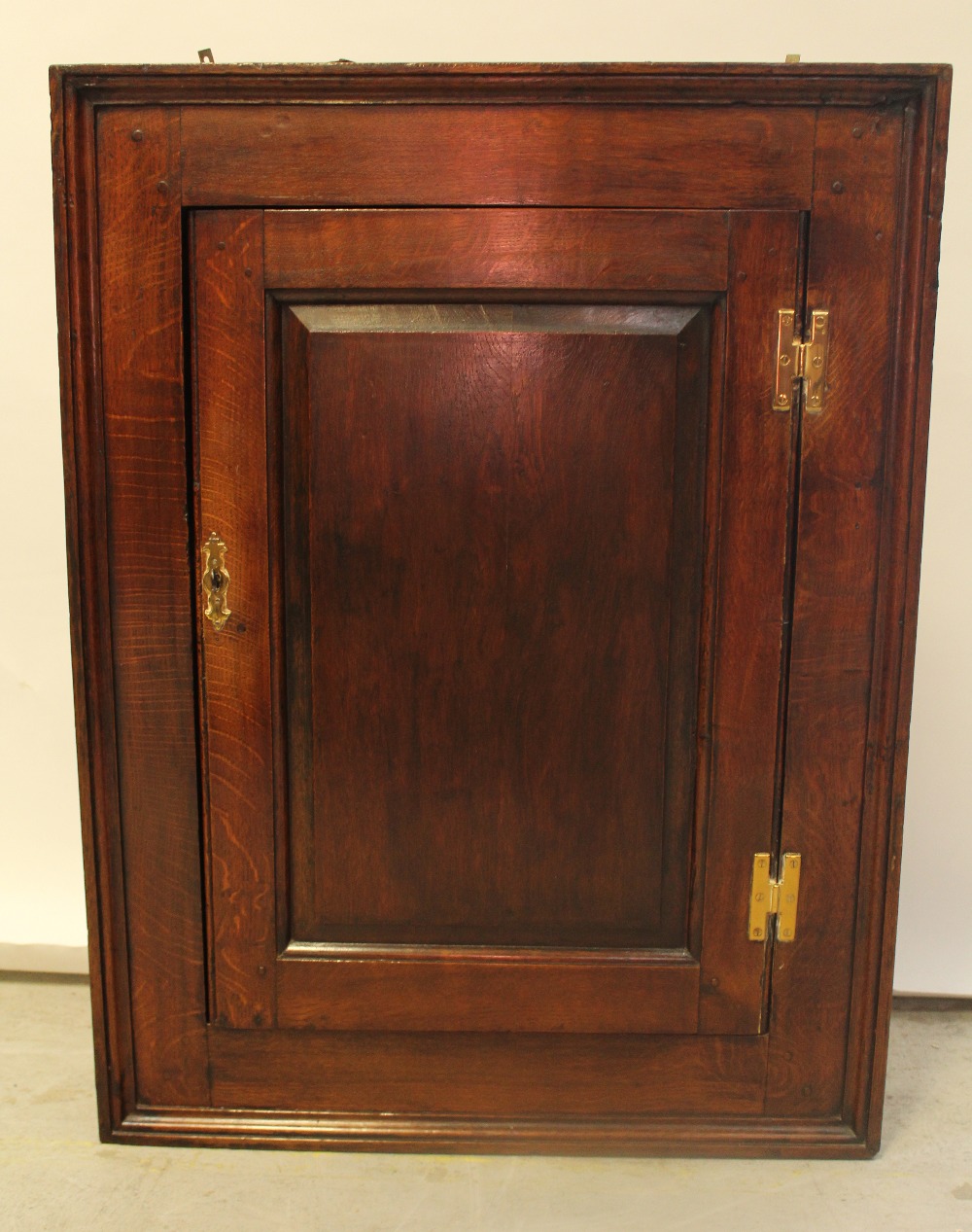 An 18th century oak flat-fronted hanging corner cupboard with H-hinges, height 91cm.