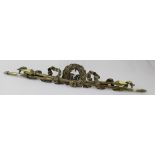 A decorative brass finial centred with a wreath and flanked by crossed spears and ribbon,