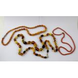 A pink coral necklace, length 54cm and two other amber-style necklaces (3).