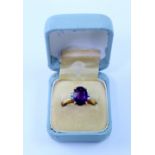 An 18ct gold dress ring, central cut amethyst flanked by two small diamonds either side,
